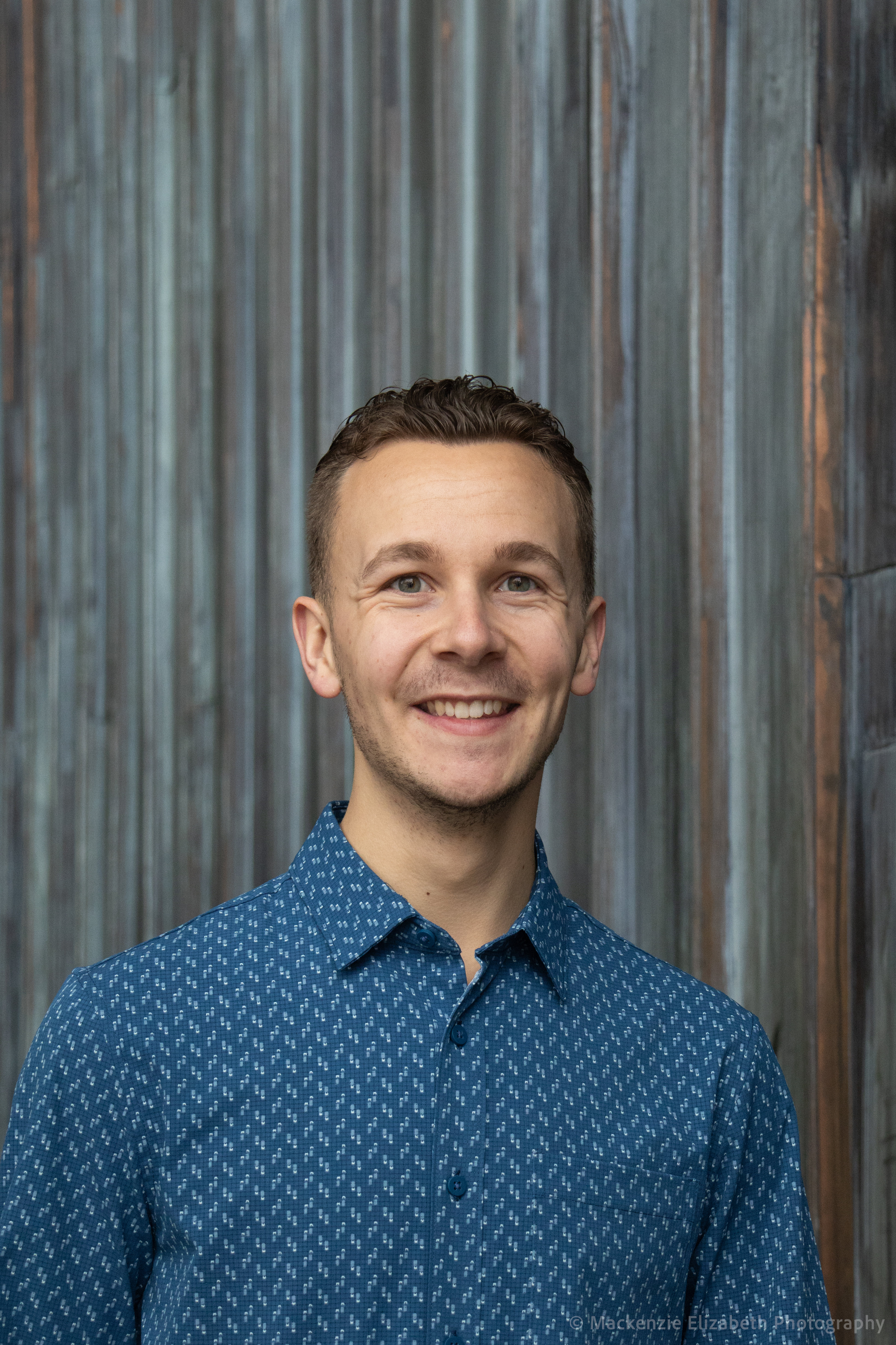 A man in blue shirt smiling for the camera.