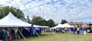 Outdoor event with people under tents.
