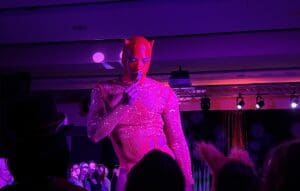 Performer in pink devil costume on stage.