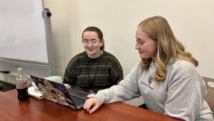 Two students collaborate on a laptop.