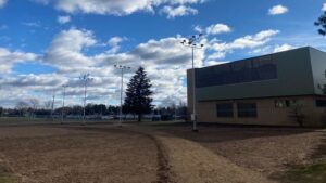 Empty field with lights and building.