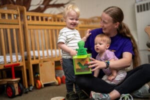 Woman with two children playing with toys.