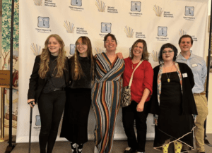 Group smiling in front of event backdrop.