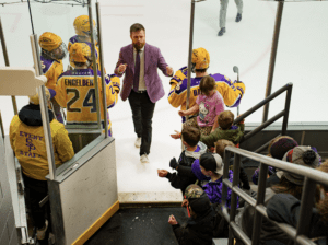 Hockey coach walking past cheering fans.