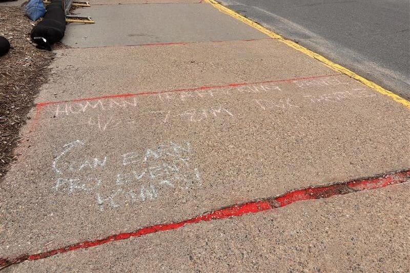 Sidewalk with chalk writing and red markings.