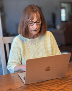 Woman with glasses working on laptop at table