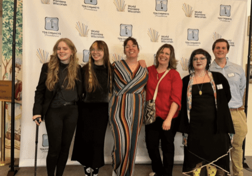 Group smiling in front of event backdrop.