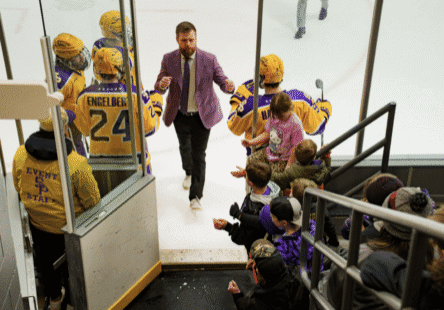 Hockey coach walking past cheering fans.