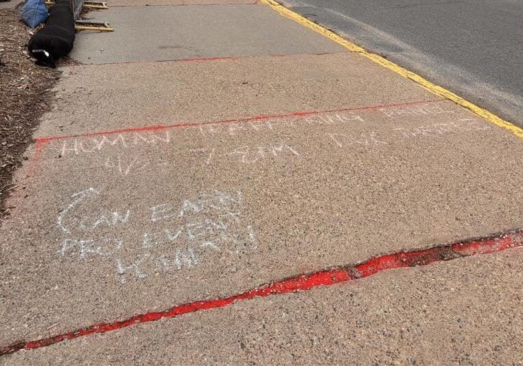 Sidewalk with chalk writing and red markings.