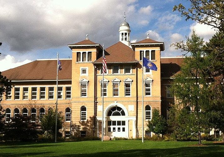 Historic building with flags and cloudy sky.