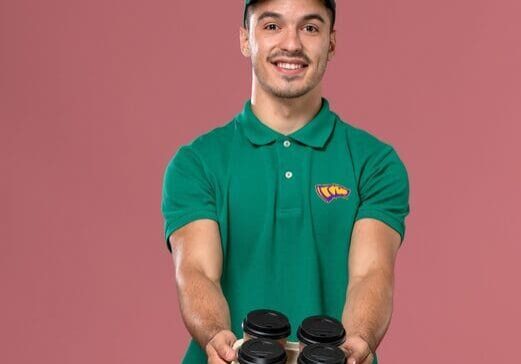Man holding coffee tray, wearing green uniform.