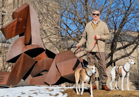 Man with two dogs near geometric sculpture.